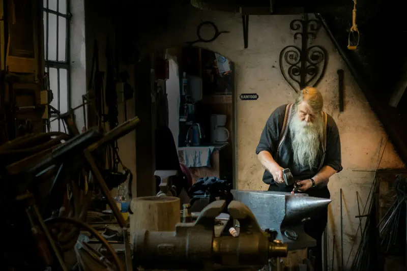 A smith holding a mallet in his workshop